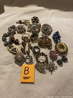 Top-down view of all items laid out showing various brooches, earrings, and a necklace in vintage style.