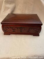 Closed view of the vintage hand carved wooden box showing the detailed leaf carvings on the front and smooth polished wood surface.
