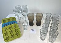 Full set of assorted glasses and silicone ice cube trays displayed on white cloth surface