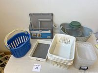 Photo of assorted plastic bins, trays, baskets and canister arranged on a table showing various sizes and colors.
