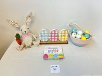 Full lot with stuffed bunny holding carrot, three painted wooden eggs on wooden stand, pastel fabric basket with painted eggs, and Easter napkins in front.
