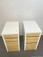 Two medium-sized file cabinets with a white frame and light wood toned drawers, each with three small drawers and one large drawer for files grouped and visible from an overhead angle.
