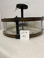 Side profile of semi flush mount ceiling light fixture showing wood and metal frame with four bulbs inside glass enclosure.