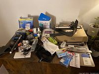 Wide view of assorted aquarium supplies on a table showing lighting fixtures, heater, multiple bottles, tools, and a protein skimmer.