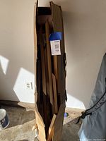 Tall, unopened shipping box containing the cedar wood components for the planter pyramid, inside a garage or similar space.