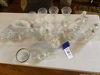 Wide view of all crystal items including goblets, pitchers, bottles, and bowls on a wooden table.