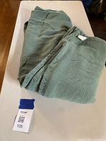 Seafoam green king size cotton blanket folded on a table, showing size and texture.