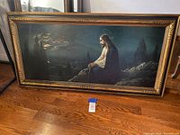Framed Jesus artwork showing full view of the painting and frame on a hardwood floor.