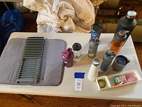 Overview of drying mat, dish rack, water bottles, and tray with small items on a table