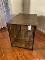 Front view showing wire metal double doors and wooden top of the dog crate.