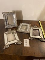 Four mirrored photo frames arranged on wooden surface showing size and detail