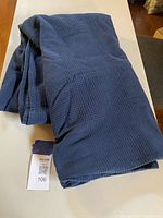 Photo of navy blue cotton king size blanket folded on a table showing the texture and color clearly.