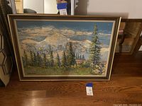 Full image of the framed painting showing the woodland scene with mountains and pine trees.