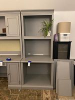 Grey Stanley bookcase and hutch with an open upper hutch section with shelving and lower open cubby area visible. Two additional shelves shown leaning beside the unit.