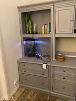 Grey file cabinet with two drawers underneath matching grey bookcase hutch with open shelves and cabinet door section. Included additional shelf for hutch is visible.