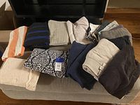 Photo showing a variety of folded towels of different colors and patterns stacked on a cushioned bench.