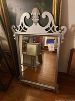 Full view of the vintage silver framed wall mirror showing rectangular mirrored glass and ornate silver frame with scrollwork and shell motif.