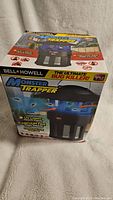 Photo of the retail box of the Bell+Howell Monster Trapper bug killer showing product branding and features including UV light and vacuum fan to trap bugs.