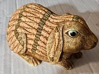 Front side view of the bunny figurine showing detailed carving of carrots forming the fur texture and large eye detail.