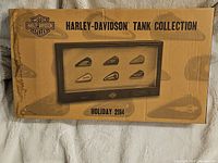 Box front showing Harley-Davidson Tank Collection with seven miniature fuel tanks in a frame, Holiday 2014 edition.