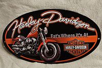 Front view of oval Harley Davidson tin sign with motorcycle image and brand text