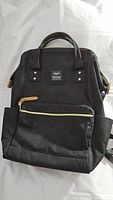 Full view of black Himawari backpack showing front pocket, side pockets, handles, and straps.