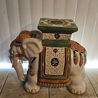 Side view of large Chinese pottery elephant stool with decorative painted details and square top