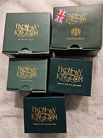 Five green Harmony Kingdom boxes with gold lettering, some with wear and a Union Jack sticker on one box corner.