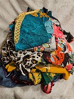 Stack of assorted plus size women's clothing showing bright, colorful fabrics with floral and animal prints.