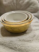 Side view of nested Hall mixing bowls, showing gold floral pattern and white interior