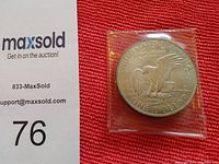 Photo of the reverse side of the 1971 Eisenhower US silver dollar coin showing the eagle landing on the moon design, with coin encased in a protective plastic sleeve.