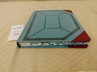 Left angled side view showing thickness and marbled endpapers of the hardcover journal