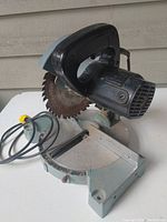 Side angle view of Delta 7-inch mitre saw showing blade, motor, and base with cord