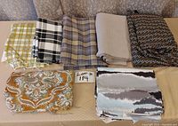 Seven fabric rolls displayed on a table showing different patterns and colors for identification.