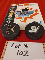 Photo of the 1972 Kingston Aces tournament program with two hockey pucks on a red background, one puck branded Fleeces, the other with Royal Bank International Championships logo.