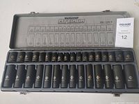 Front view of Mastercraft 32-piece impact socket set in gray metal case, showing black impact sockets organized in labeled slots with size designations.
