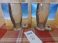 Two Molson Canadian 20 oz beer glasses in front of their original boxes showing brand logo and wheat field design.