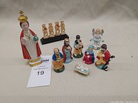 Image showing the entire set of nativity and additional monkey and priest figurines with a MaxSold label.