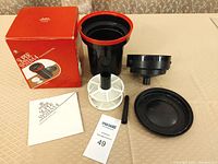 Complete Paterson Super System 4 film developing tank kit with parts arranged - tank, reels, lid, base, instruction manual, and box.