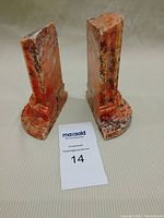Pair of red marble bookends side by side showing front and side profiles, revealing the shape and veining.