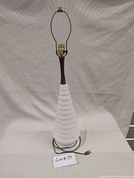 Full view of retro table lamp showing ceramic ridged base, wooden neck, and electrical cord