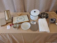 Full lot arranged on table showing all kitchen items including the enamel pot, trays, potato press, electric carving set, glass bowl, and tablecloth.