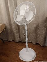 Front angle view of the white 18-inch floor fan showing the three blades and base.