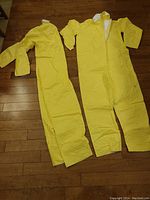 Two yellow Tyvek coated coveralls laid out showing full length, sleeves, and front zipper.