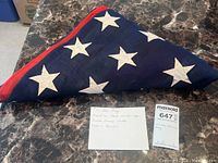 Triangularly folded flag on marble table with handwritten note and lot card visible