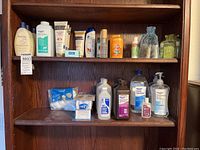 Wooden shelf containing assorted lotions, baby powder, bandages, cotton swabs, and hand sanitizers.