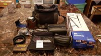 Overview of the lot including cameras, bags, tripod, monopod, and accessories arranged on a table.