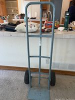 Front view of metal two-wheel hand truck dolly with gray frame and black tires.