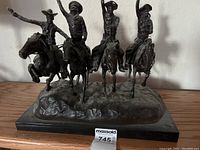 Front view of full bronze sculpture showing four horseback riders mounted on marble base