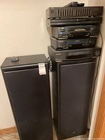 Full view of two KLH speakers side by side with the stack of video and audio equipment.